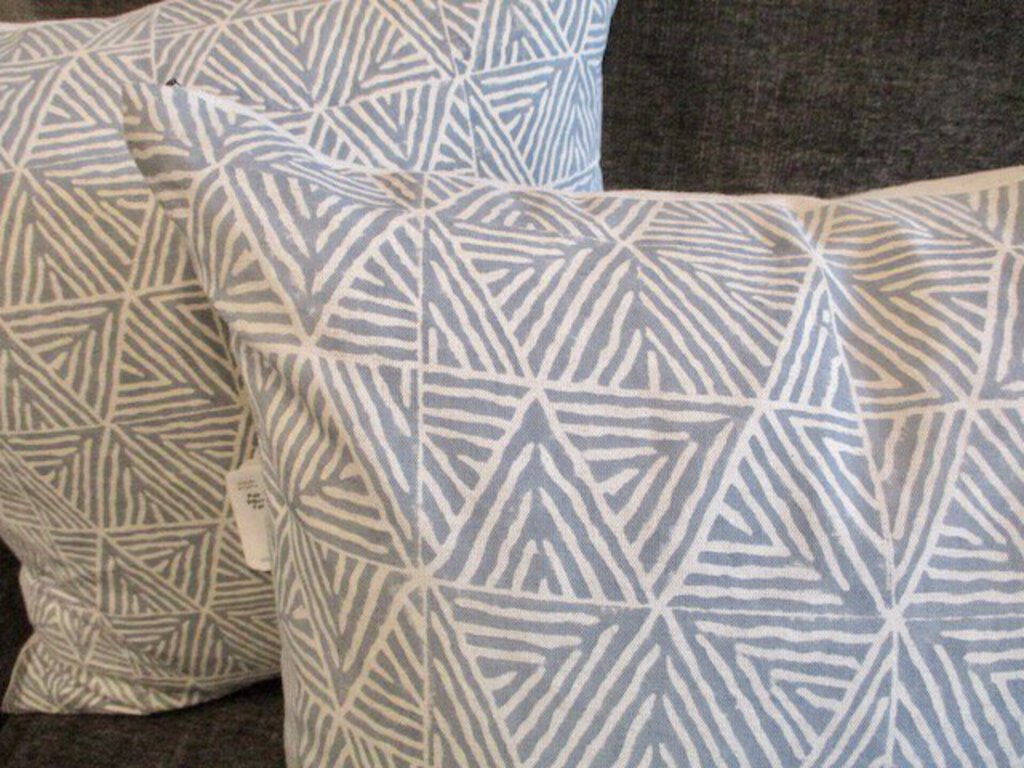 Close-up of decorative cushions with blue and white geometric triangle pattern on a dark fabric sofa