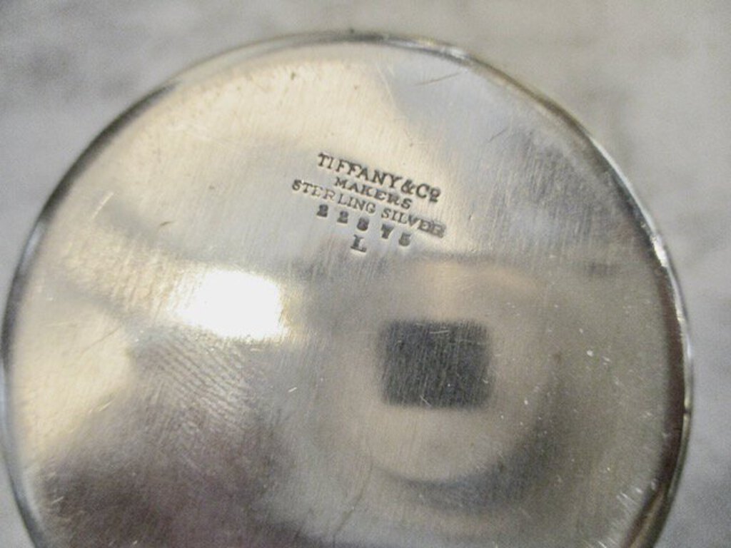 Close-up of Tiffany & Co sterling silver hallmark and maker's mark on a round silver object