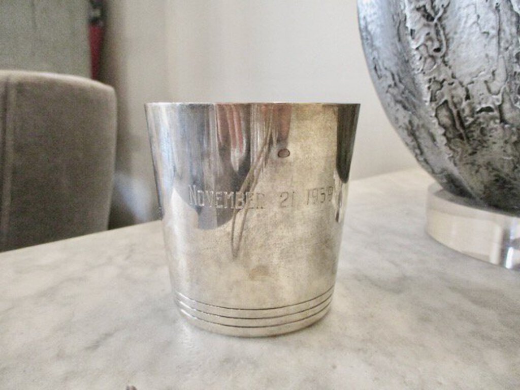 Vintage silver metal cup with engraved date November 21 1958 on marble surface