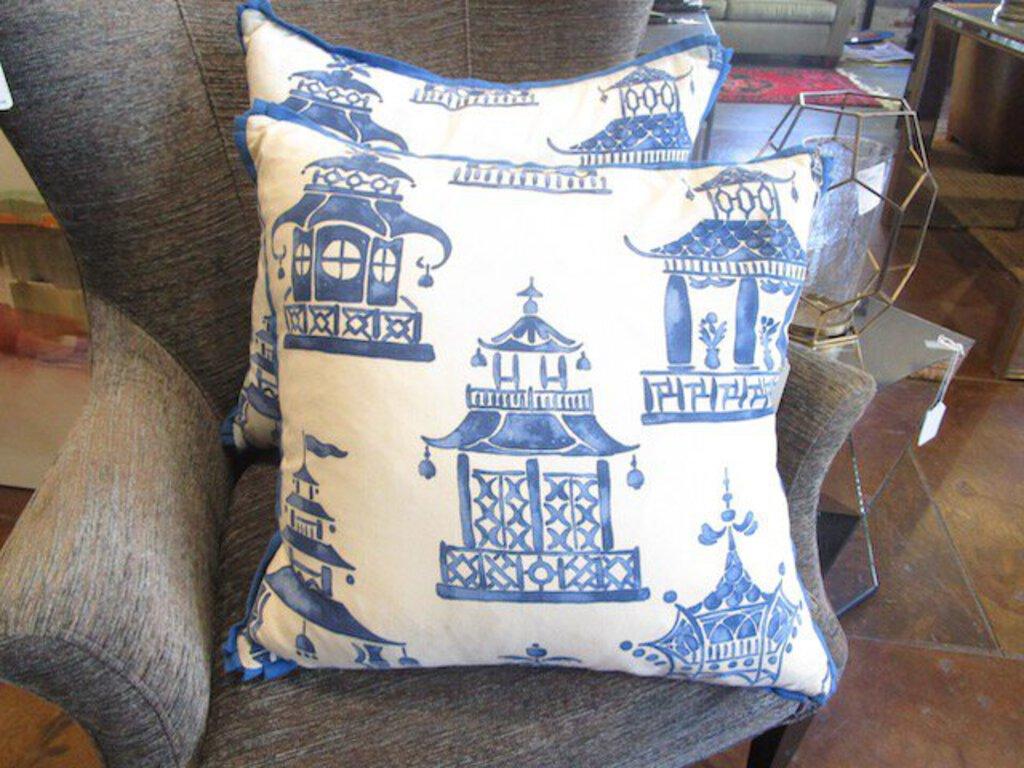 Designer fabric pillows with blue pagoda prints on gray armchair in furniture store